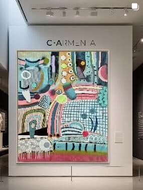 Pintura enmarcada expuesta en una galería bajo el rótulo C·ARMENTA