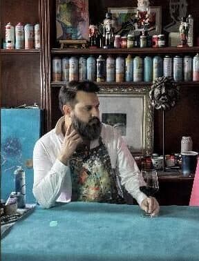 Cristian Armenta en su taller, rodeado de latas de aerosol y pintura